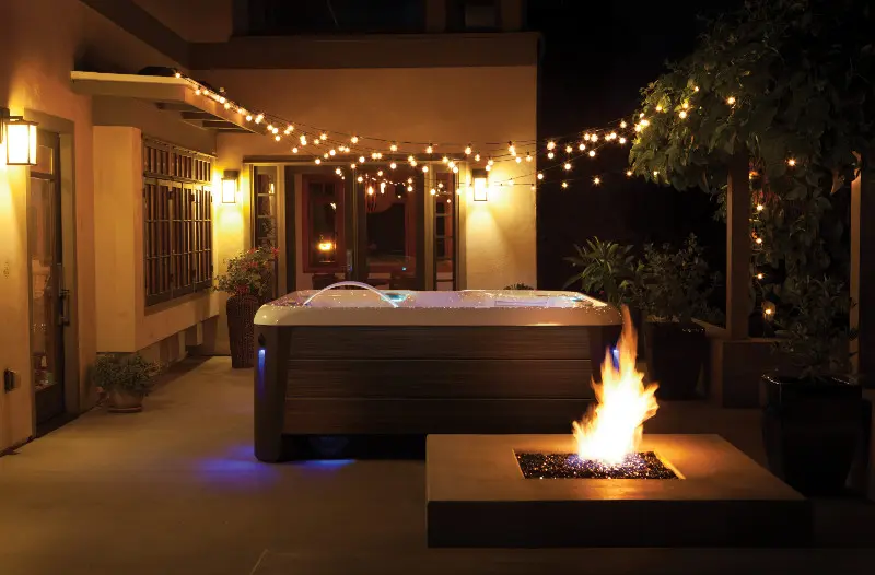 HotSpring Spa's 3 HotSpring Highlife Aria op een verlicht terras met vuurtafel