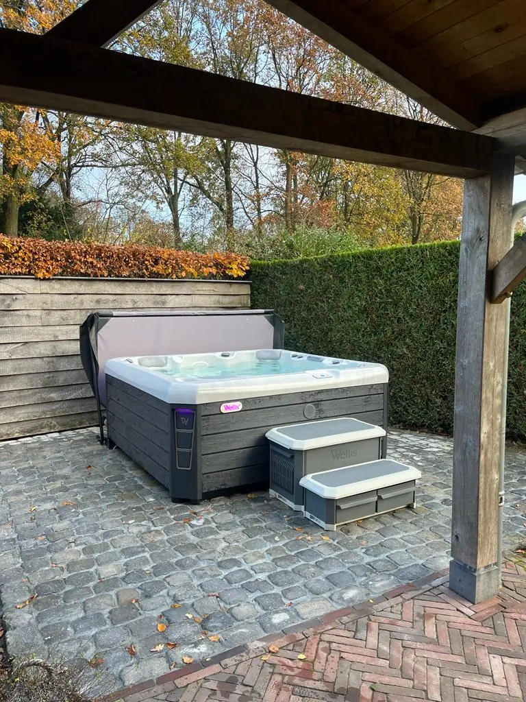 Wellis jacuzzi onder een houten overkapping in de tuin